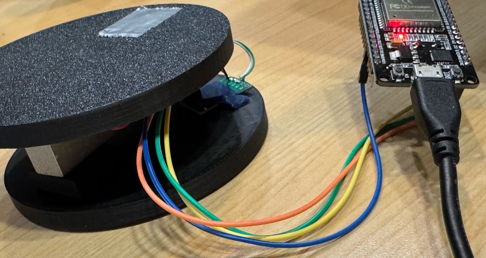 Prototype scale with circular plates, strain gauge bar, HX711 module, and ESP32 dev board wired together on a bench